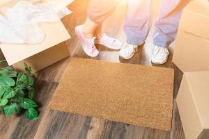 homme et femme debout près du tapis de bienvenue home sweet home, boîtes de déménagement et plante photo