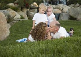 un couple affectueux s'embrasse sous le regard de jumeaux mignons photo