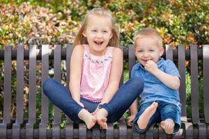 jeune soeur et frère s'amusant sur le banc du parc photo