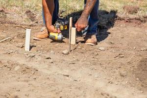 travailleur installant des piquets et des guides de bois sur le chantier de construction photo