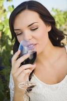 Jeune femme adulte en dégustant un verre de vin dans le vignoble photo