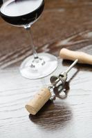 verre à vin abstrait, liège et tire-bouchon posés sur une surface en bois réfléchissante. photo
