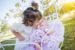 adorable jeune fille jouant avec une poupée et un chariot photo