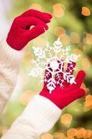 femme portant des mitaines rouges saisonnières tenant un ornement de noël flocon de neige blanc photo