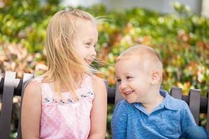 jeune soeur et frère s'amusant sur le banc du parc photo