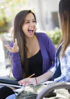 jeune femme métisse expressive assise et parlant avec sa petite amie photo