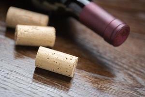 bouteille de vin et bouchons sur un résumé de surface en bois réfléchissant. photo