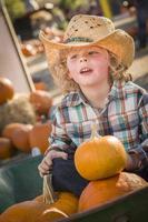 petit garçon au chapeau de cowboy au champ de citrouilles photo