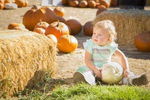 adorable petite fille tenant une citrouille au champ de citrouilles photo