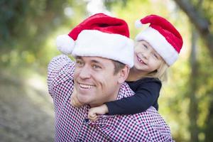 père et fille s'amusant à porter des chapeaux de père noël photo