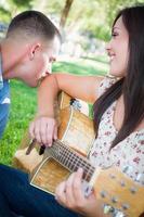 jeune fille adulte jouant de la guitare avec son petit ami dans le parc. photo