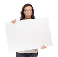 femme de race mixte aux yeux écarquillés tenant une pancarte blanche sur blanc photo