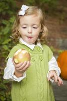 adorable enfant fille mangeant une pomme rouge à l'extérieur photo