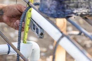 plombier utilisant un niveau et un ruban à mesurer lors de l'installation d'un tuyau en pvc sur un chantier de construction photo