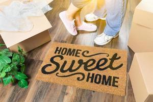 homme et femme debout près du tapis de bienvenue home sweet home, boîtes de déménagement et plante photo