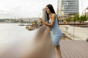 jeune femme à l'aide d'un téléphone mobile en se tenant debout sur la promenade du fleuve photo