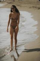 jeune femme en bikini marchant au bord de la mer un jour d'été photo