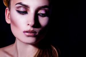 portrait à contraste élevé d'une belle jeune femme adulte avec maquillage et peau saine sur fond noir photo