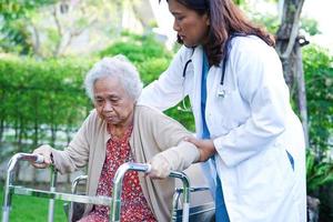 médecin aide une femme âgée asiatique handicapée à marcher avec une marchette dans le parc, concept médical. photo