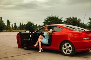 jeune femme sexuelle sur des talons hauts dans une voiture rouge photo