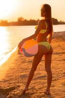 adorable dame mince en maillot de bain avec ballon de plage dans la mer photo