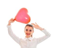 jeune fille souriante tenant un gros ballon en forme de coeur et leva les mains au-dessus de sa tête photo