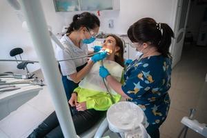 dentiste et assistant soignent les dents d'un patient photo