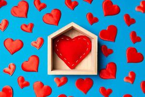 gros plan sur un coeur rouge dans une maison en bois décorée de petits coeurs sur fond coloré. La Saint-Valentin. concept de maison douce maison photo