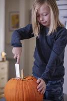 beau garçon blond découpant une citrouille avec un couteau pour halloween. notion d'halloween photo