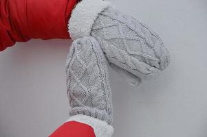 mains féminines en mitaines tricotées chaudes grises avec fourrure blanche. accessoires d'hiver de noël. protection des mains contre le vent et le froid. photo
