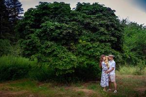 belle jeune famille portant une petite fille et se sourit au parc verdoyant photo