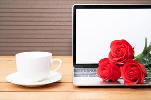 rose rouge et tasse à café avec maquette d'ordinateur portable sur bois photo
