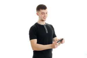 joyeux jeune homme debout dans un t-shirt noir et comprend de la musique au téléphone photo