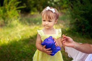 drôle de petite fille avec son jouet préféré dans les mains en regardant le jardin verdoyant photo