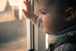 mignonne petite fille regardant par la fenêtre photo