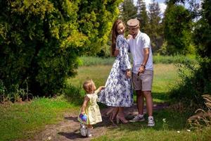 une famille heureuse joue avec sa petite fille au parc vert photo