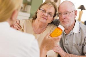 médecin ou infirmière expliquant les médicaments sur ordonnance à un couple de personnes âgées photo