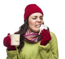 une femme métisse malade boit du thé chaud en se mouchant photo