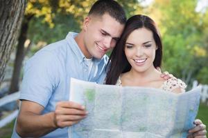 couple mixte regardant par-dessus la carte à l'extérieur ensemble photo