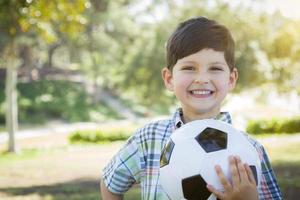mignon jeune garçon jouant avec un ballon de soccer dans le parc photo