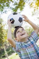 mignon jeune garçon jouant avec un ballon de soccer dans le parc photo