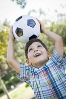 mignon jeune garçon jouant avec un ballon de soccer dans le parc photo