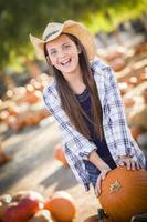 Preteen girl jouant avec une brouette au champ de citrouilles photo