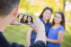 un homme prend une photo de sa femme et de sa fille sur son téléphone portable