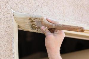 peintre professionnel coupant avec un pinceau pour peindre le cadre de la porte de la maison. photo