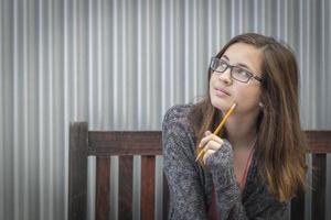 jeune étudiante rêveuse avec un crayon regardant sur le côté photo