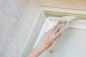 peintre professionnel coupant avec un pinceau pour peindre le cadre de la porte de garage photo