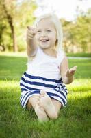 jolie petite fille assise et riant dans l'herbe photo