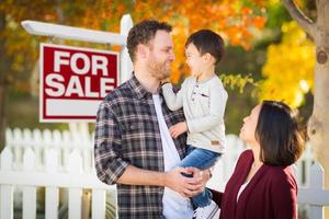 parents et enfants métis chinois et caucasiens devant la clôture et à vendre enseigne immobilière. photo