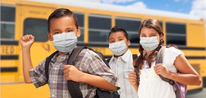 étudiants hispaniques près d'un autobus scolaire portant des masques faciaux photo